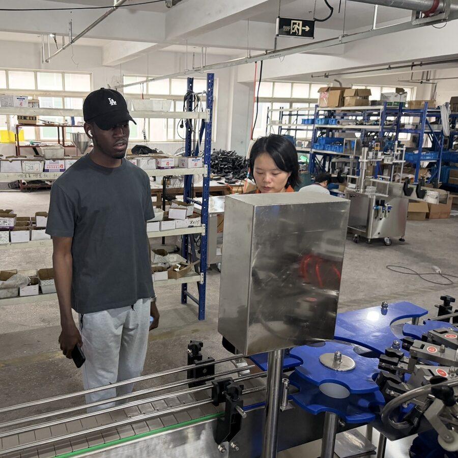 Youman standing beside a bottling and labelling line inside a Chinese factory.